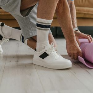 Close-up of a yoga mat and water bottle on a wooden floor.