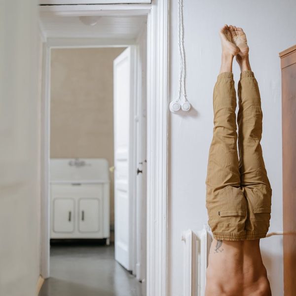Man performing a controlled stretching exercise in a minimalist room.